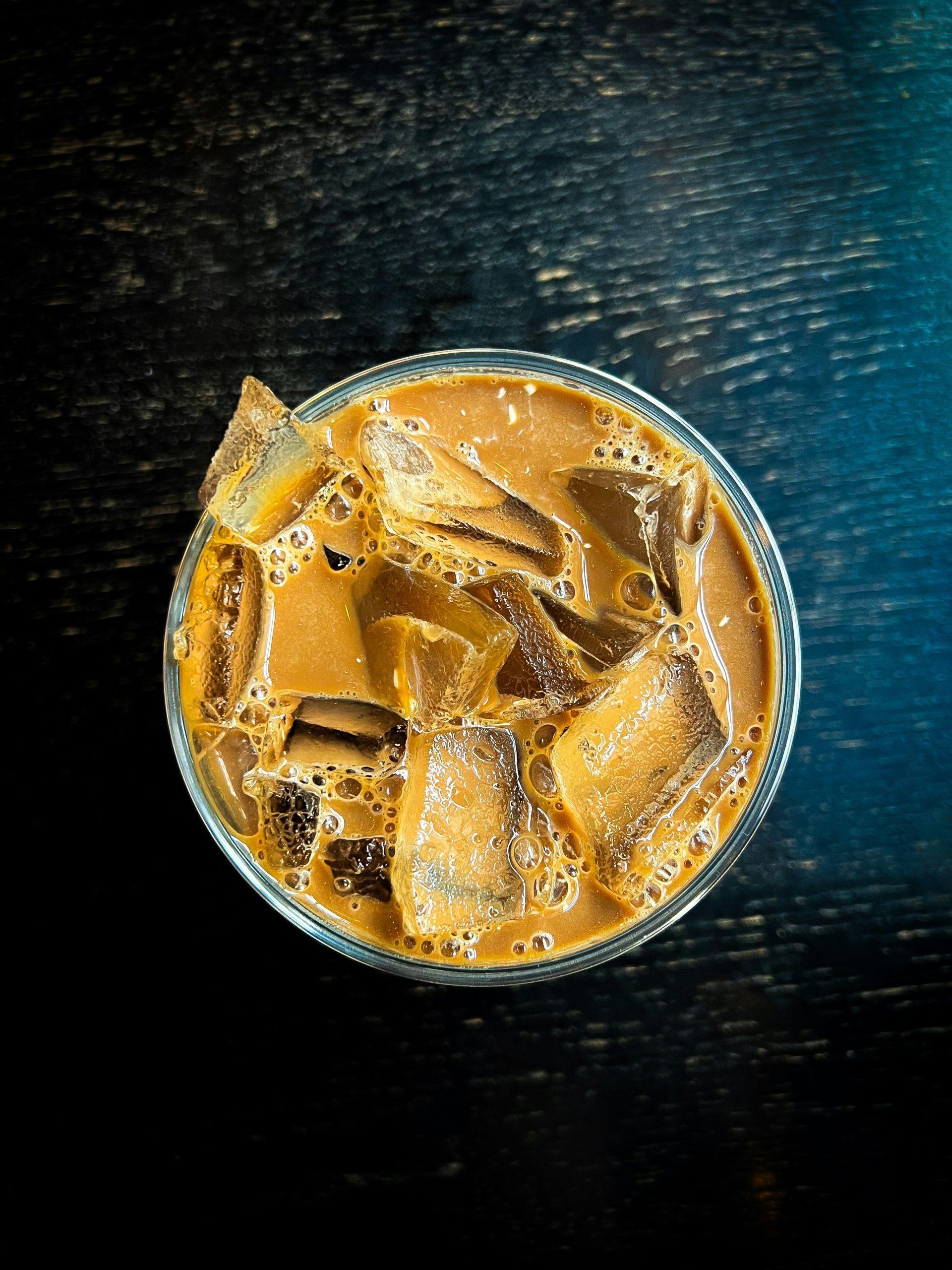 a glass of beer with ice cubes in it